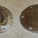 Last step.  My cover plate was seriously scored.  On the left we see black marks; they are actually recesses, not easily photographed, but surprisingly deep.  Maybe some sand got in between the impeller and plate somewhere along the line.  So out to the belt sander, starting at 50 grit and running up to 320.  After almost 30 minutes of sanding (and several burns on my fingers from the hot metal THROUGH MY WELDING GLOVES), the plate was pretty flat again.  Then it was onto a glass plate with some 400 and then 600 grit wet and dry for a final polish.  The image on the right is the result; you can see the reflection of the fastener drawers.  I'm happy.